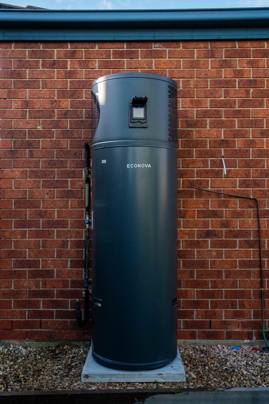 A Goldsure plumber connecting an Econova hot water heat pump at a home