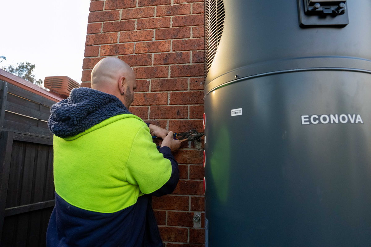 A Goldsure plumber connecting the pipework on a hot water heat pump install