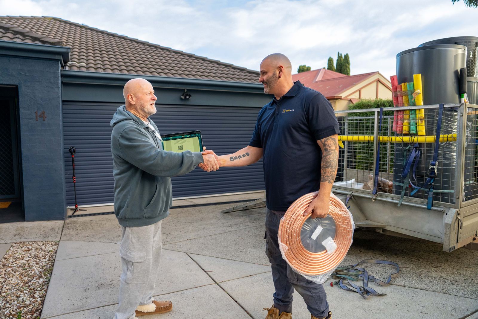 A Goldsure estimator shaking hands with a homeowner after showing the quote on a tablet